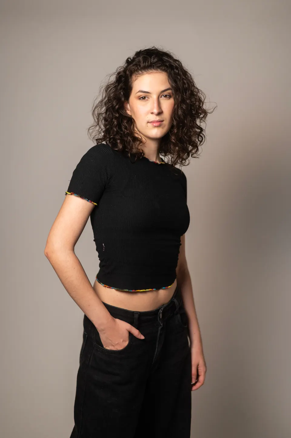 Mulher de cabelos curtos e cacheados, blusa preta, em retrato de meio corpo